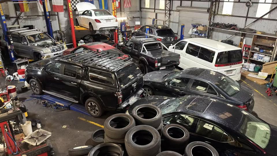 Busy Tyre Select workshop with vehicles on lifts and tyres in the foreground.